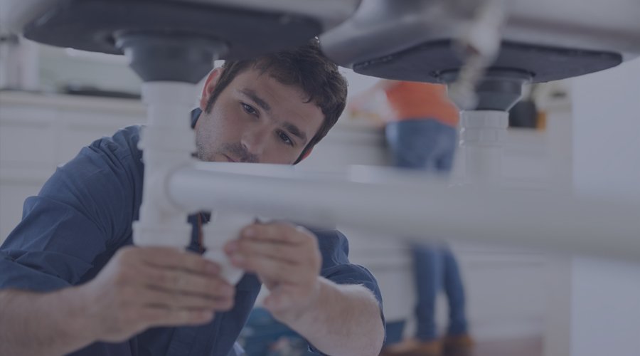 Plumber fixing the pipes in a woman's kitchen.