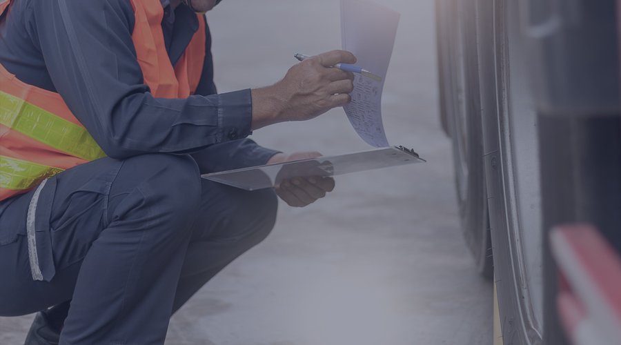 Employee holding a clipboard and inspecting tires on a truck.