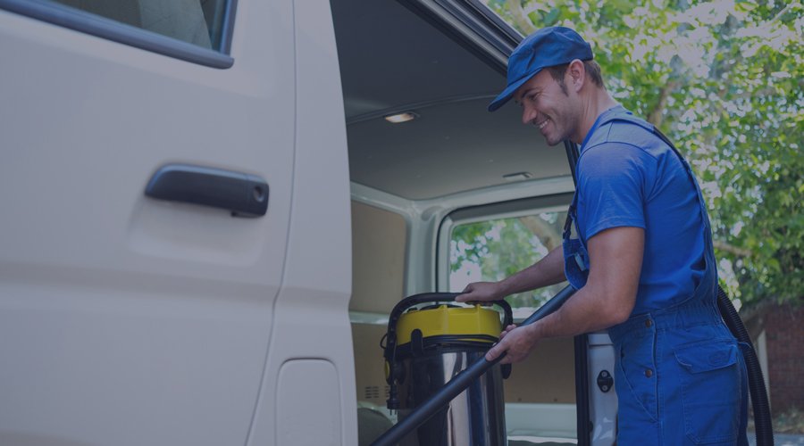 Cleaning service employee taking supplies out of a van.